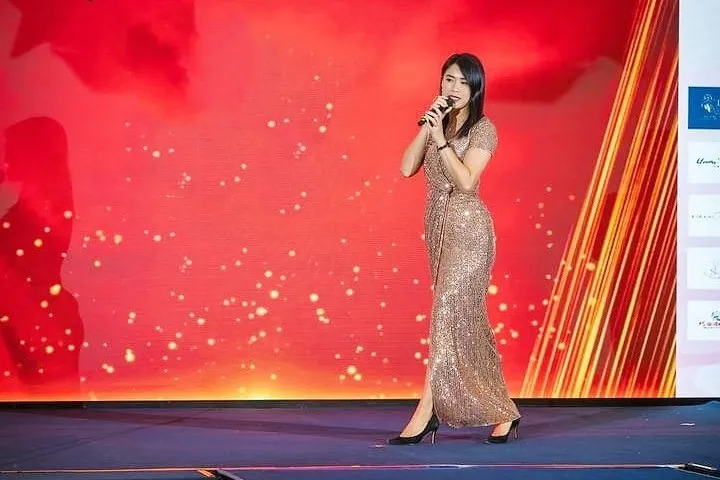 Michelle Lim speaking on stage with a microphone at an event.