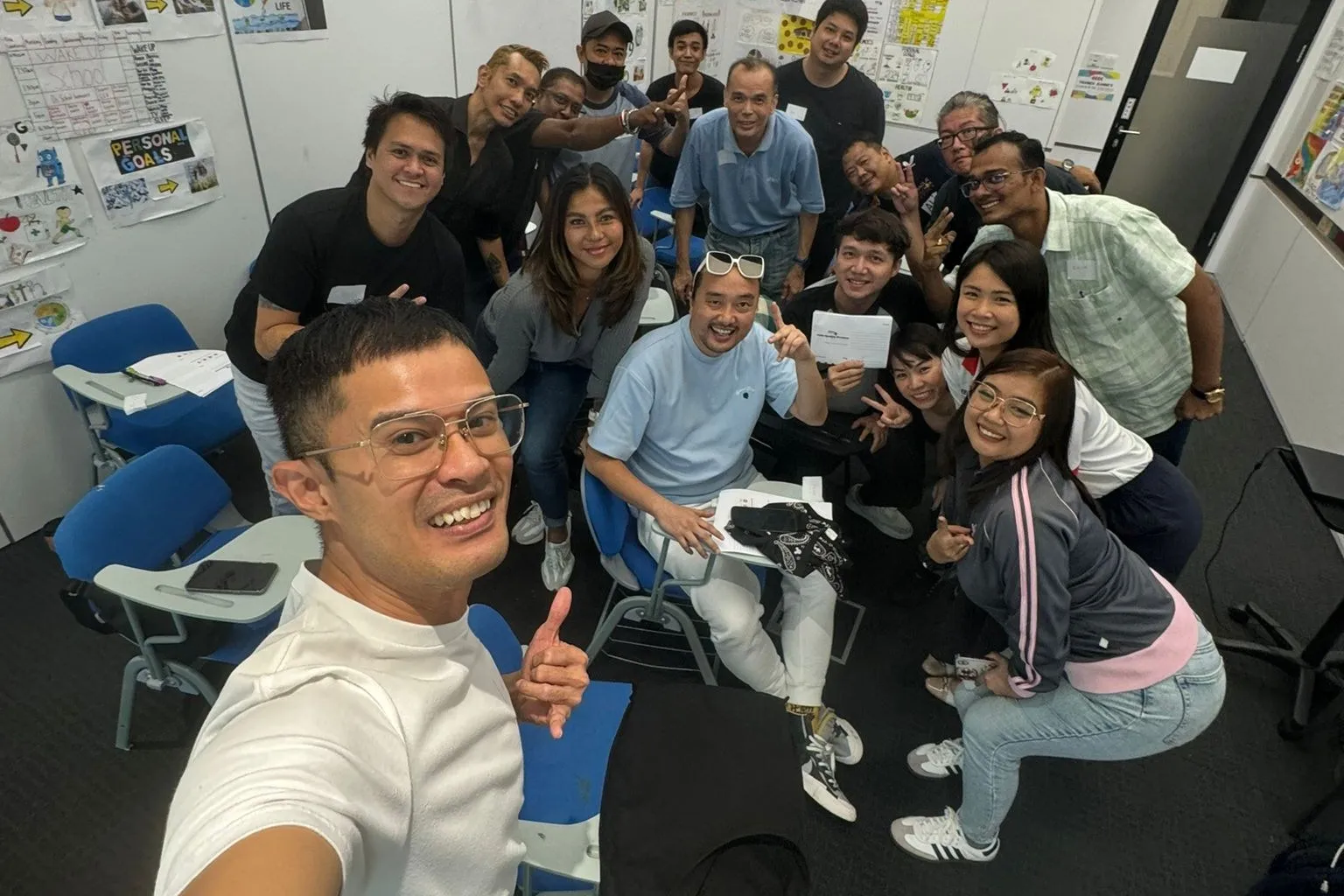 Smiling workshop participants gathered together for a group selfie in a training room.