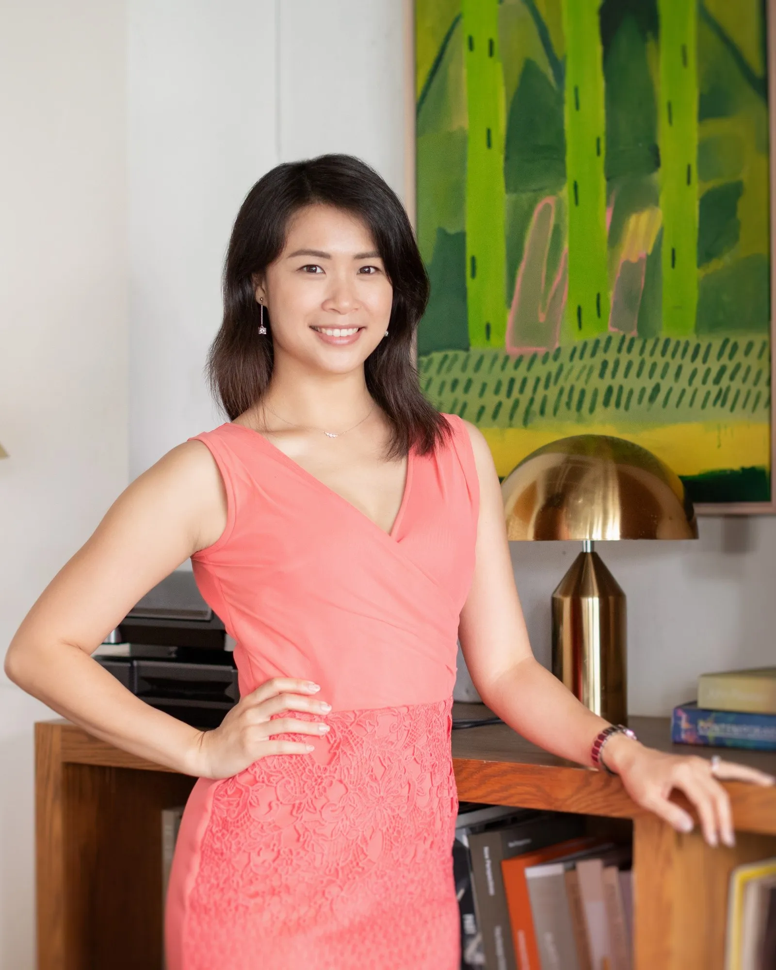Portrait of Michelle Lim smiling, standing beside a bookshelf.