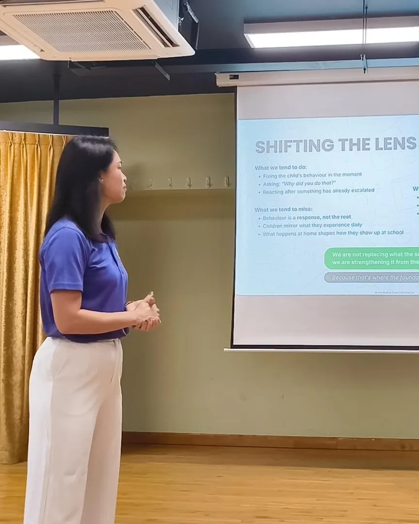 Michelle Lim presenting a workshop, turning towards her slide.